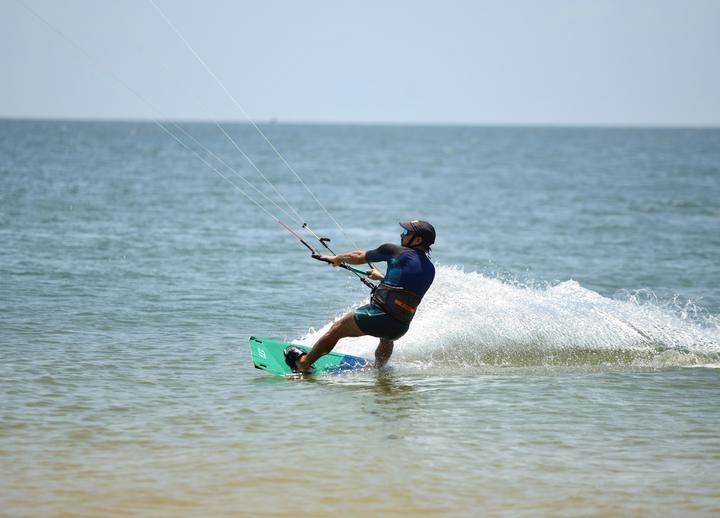 Kitesurfista velejando e levantando água