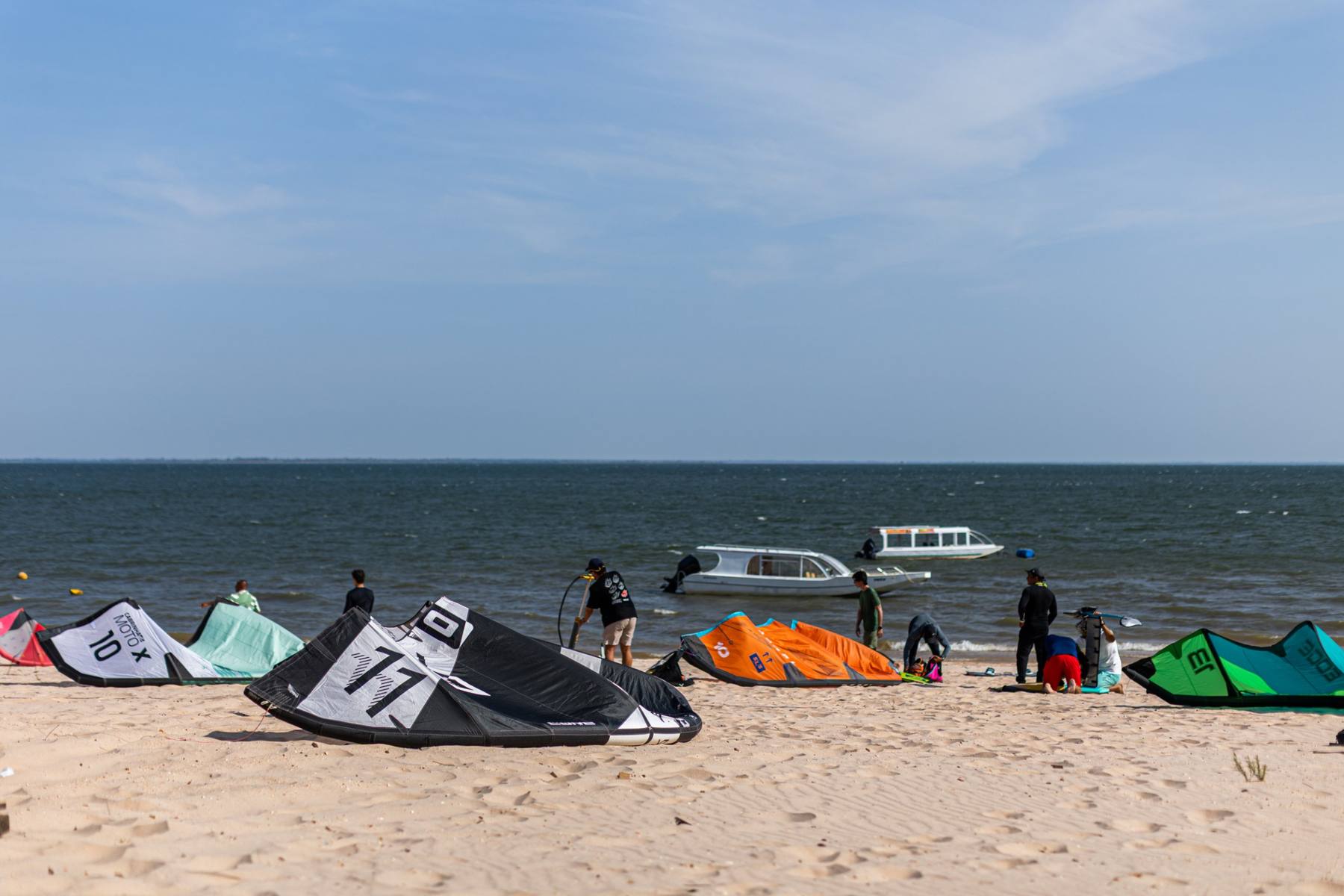 Pipas coloridas na areia e barcos no rio